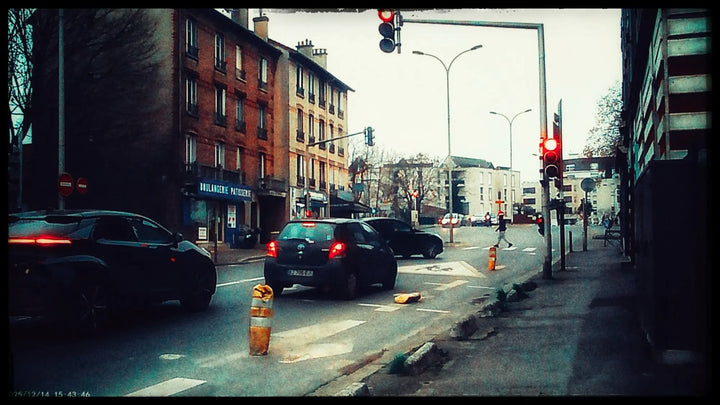 Overcast afternoon. Tail-lights and signs come back louder than they were, and the sky has gone flat white.